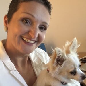 A photo of Dr Aida Hurem, a middle aged, Middle-Eastern woman with short hair, holding a a fluffy Chihuahua and smiling.