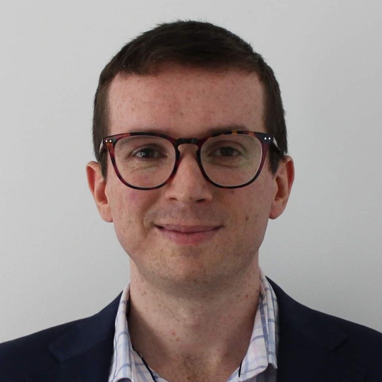 Dr Chris Edwards. A freckled man in his thirties, with large round glasses, smiling