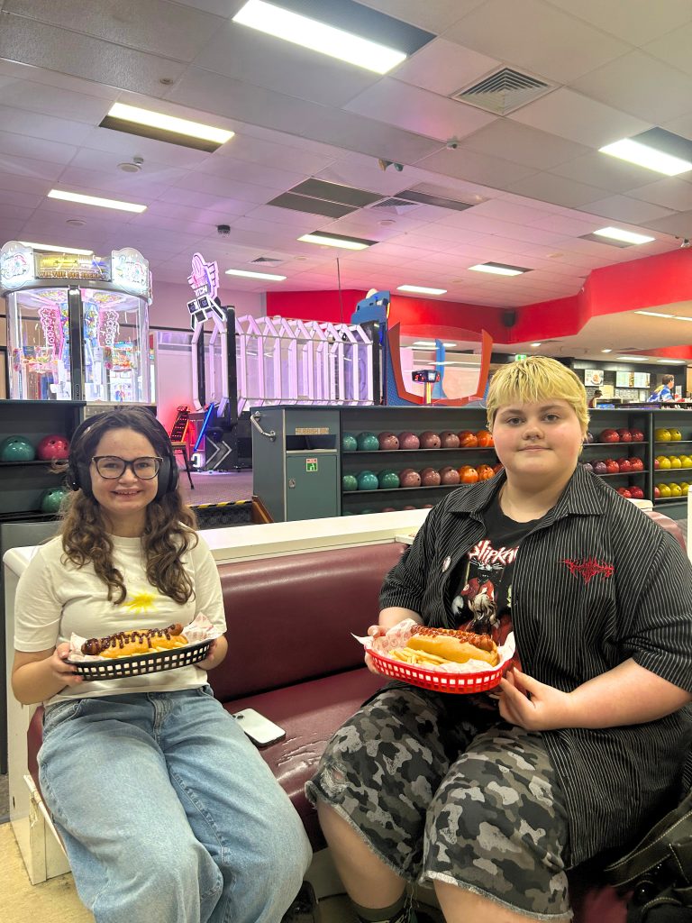Ella and Wren, eating hotdogs in a bowling alley, at a Youth Peer Group outting.